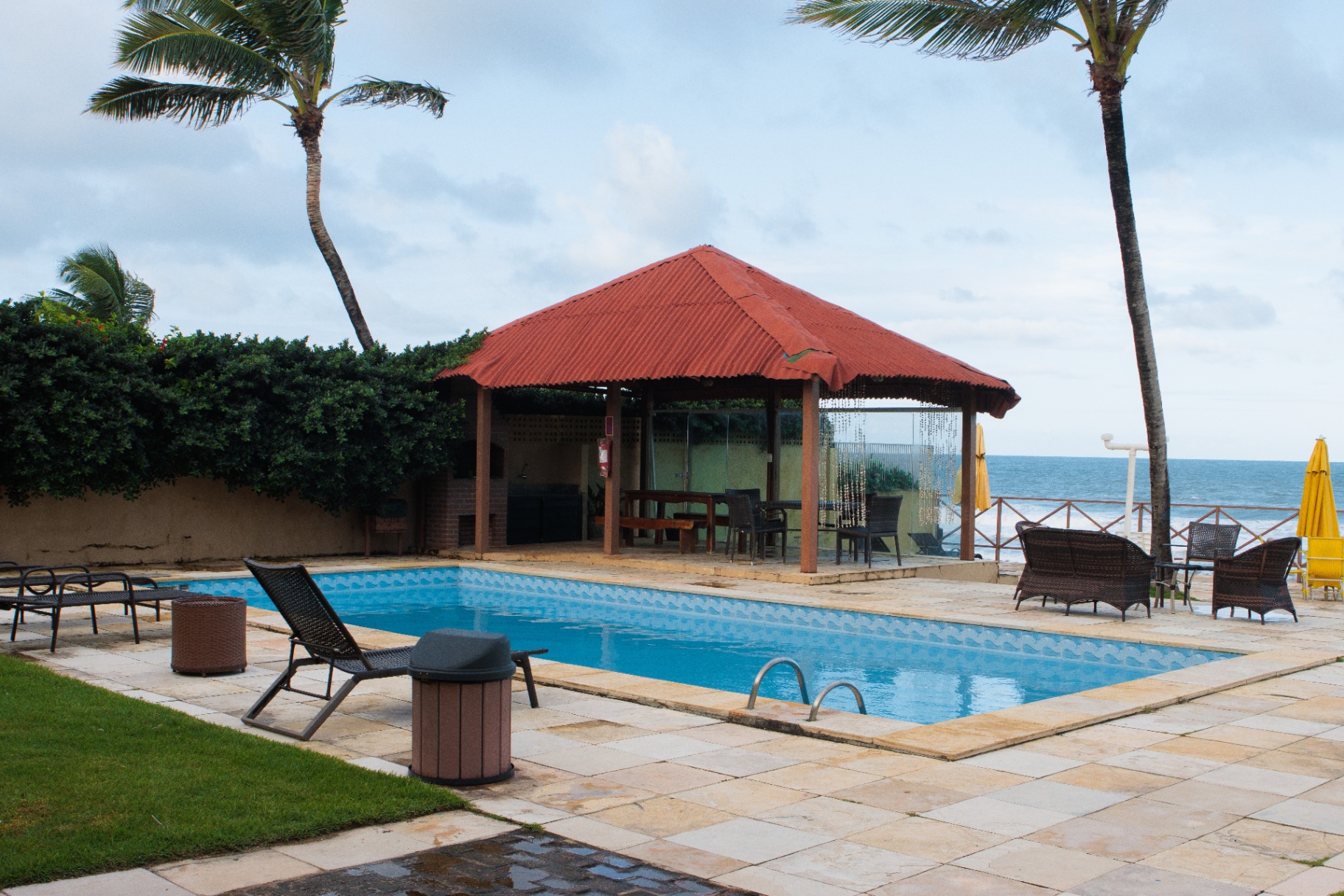 Piscina da Pousada Maria Bonita com deck coberto, coqueiros e mar ao fundo